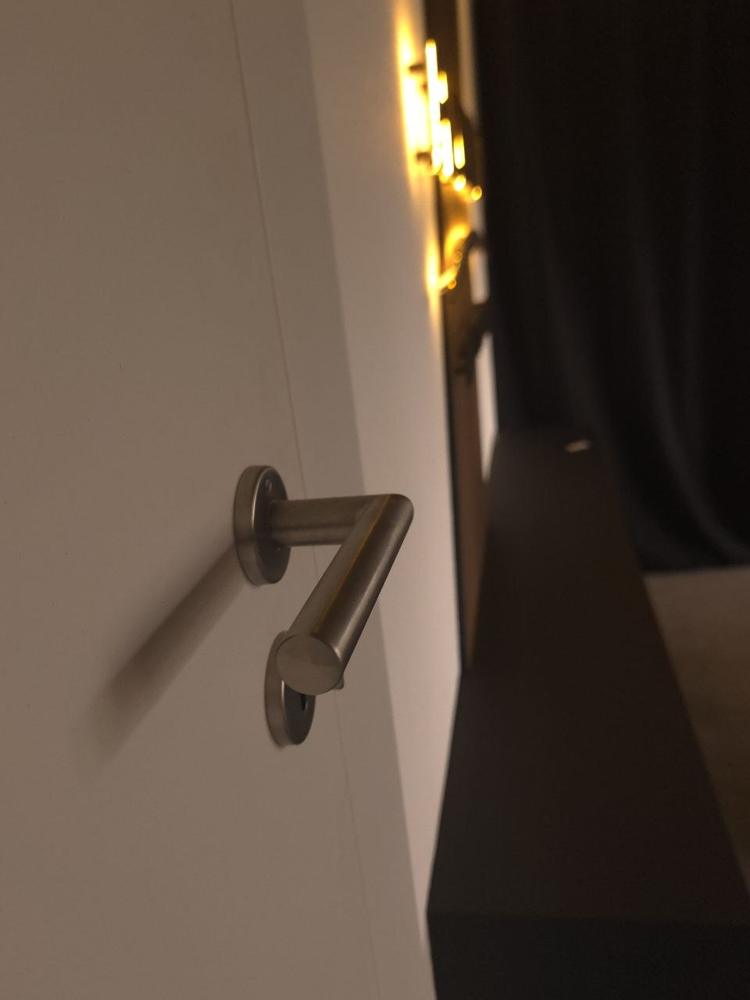 Türdrücker in Edelstahl, im Hintergrund das Licht der Wand