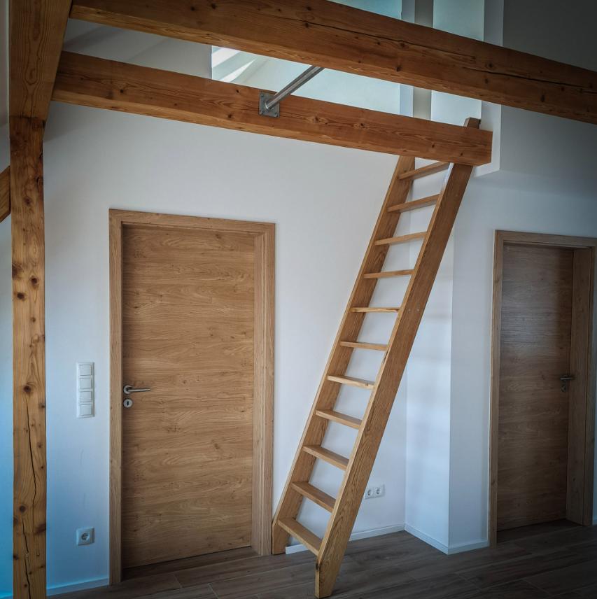 Leitertreppe zwischen zwei Türen unter einem Holzbalken